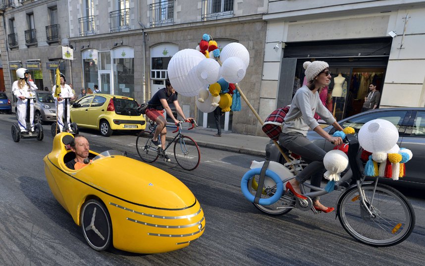 Бициклијада у Вело-граду у Нанту - жена вози бицкл украшен балонима поред човјека у мини тркаћем аутомобилу